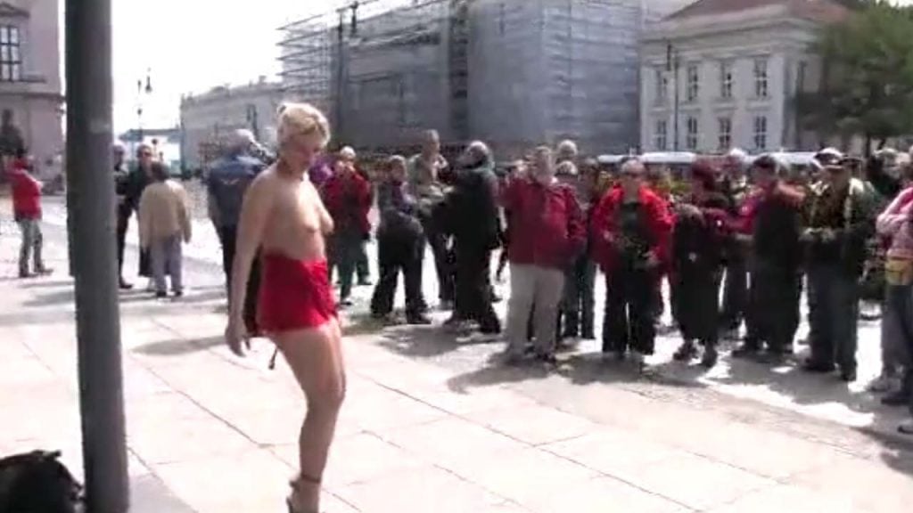 Beautiful blonde girl naked and restrained in public with crowd of onlookers