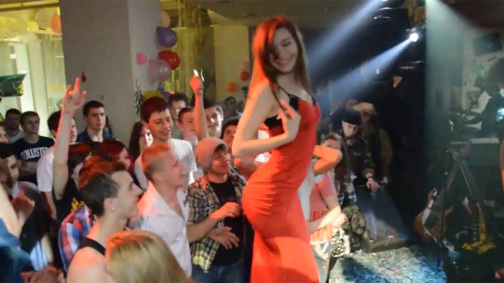 Sensual girl in red dances and strips naked on stage during a live concert